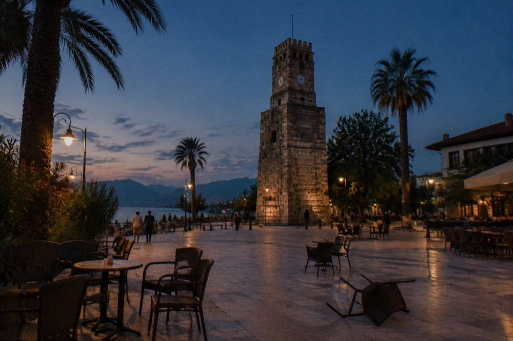 A stone clock tower rising above a small square in Antalya old town