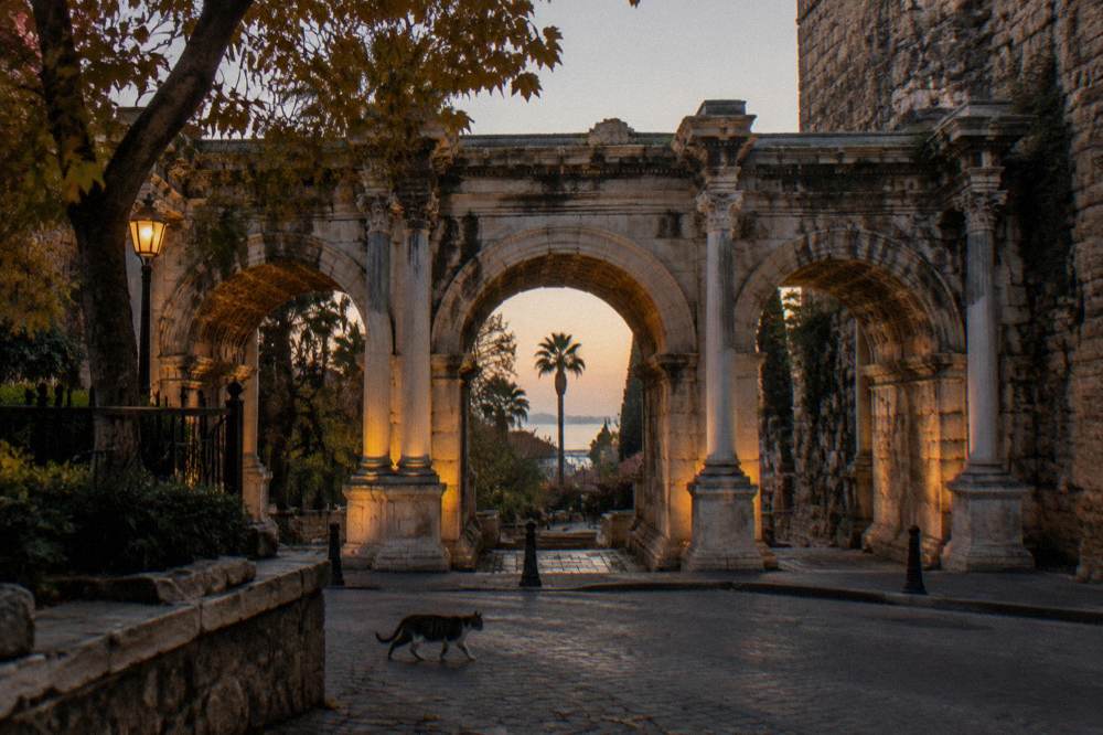 A stone archway of Hadrian's Gate seen from the old town street in Antalya