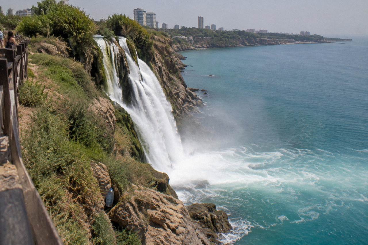 A waterfall dropping over a cliff edge toward the sea below