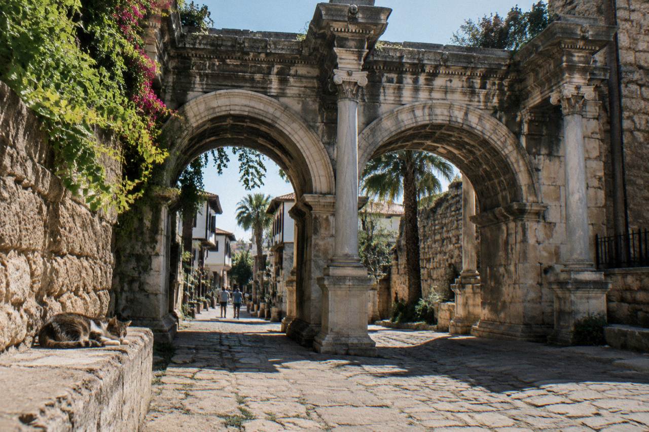 A stone archway of Hadrian's Gate standing over a street in Antalya old town