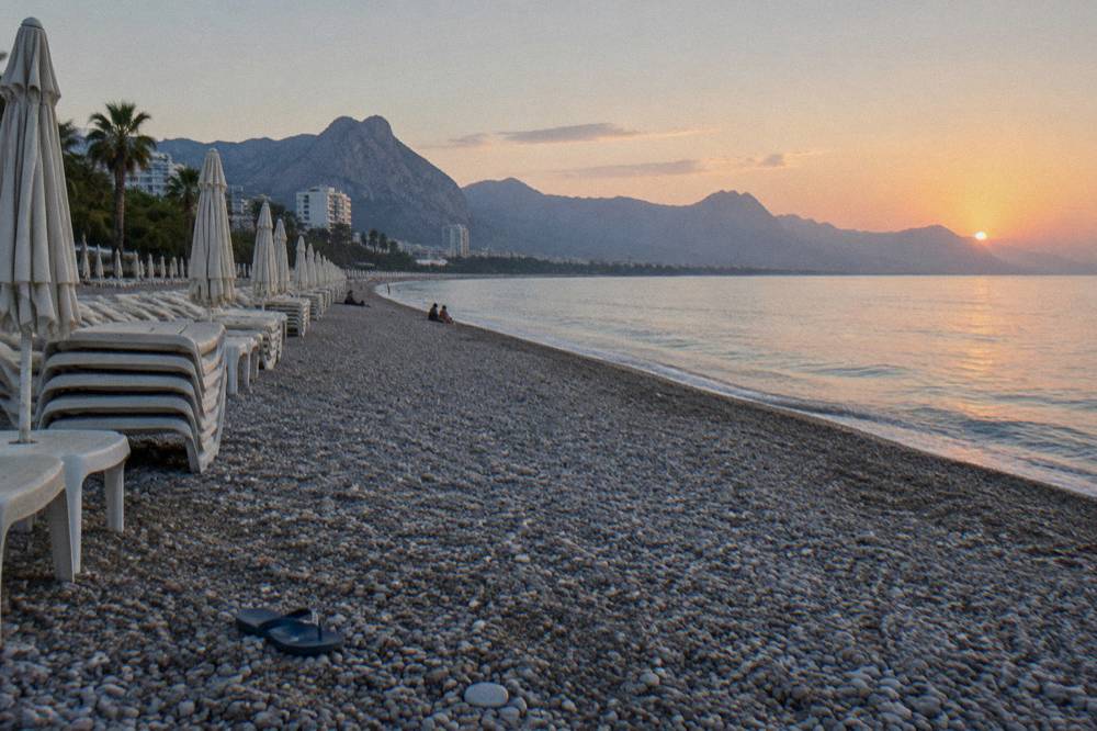 Sun loungers and umbrellas in rows on a pebbly Konyaalti shoreline