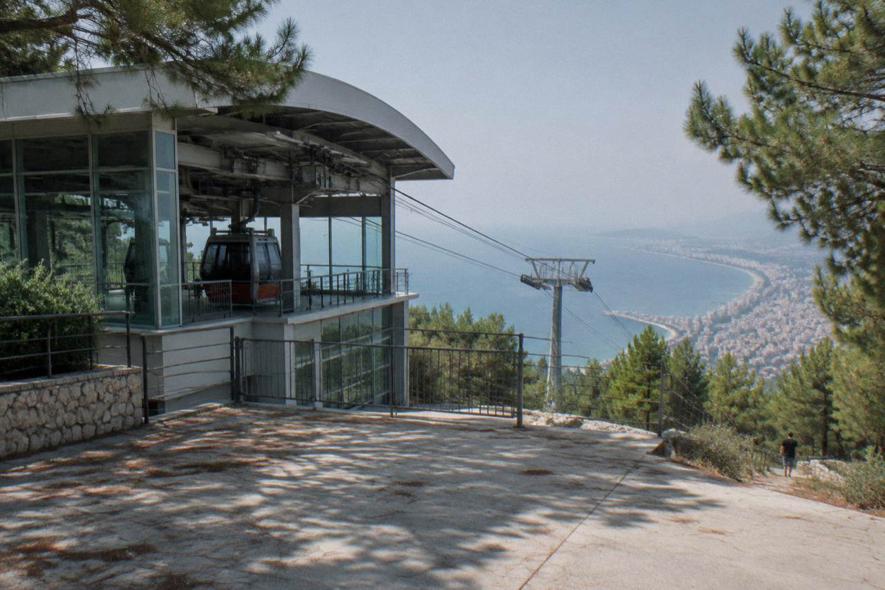 A cable car station building on a forested hill above the Antalya coastline