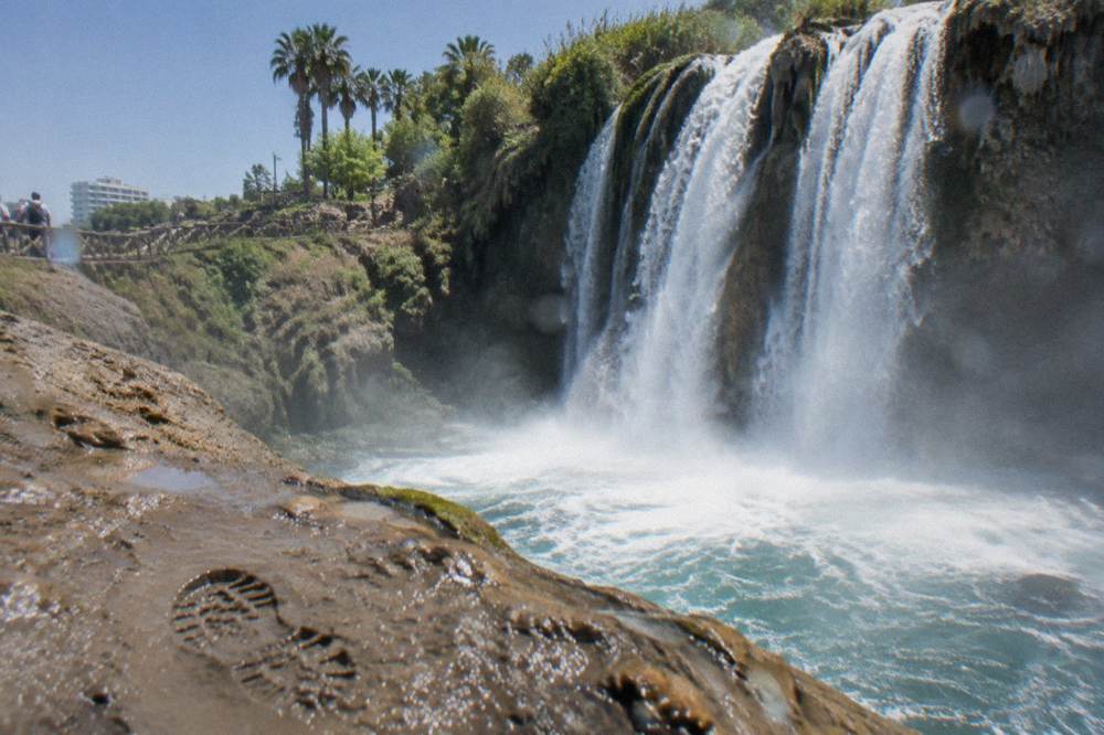 Water falling in a wide curtain over a cliff face into a pool