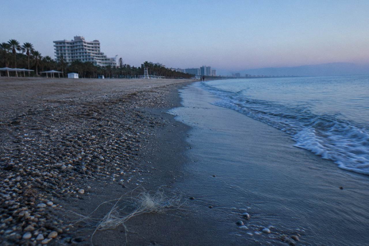 An empty Antalya beach with a mix of sand and pebbles along a calm sea