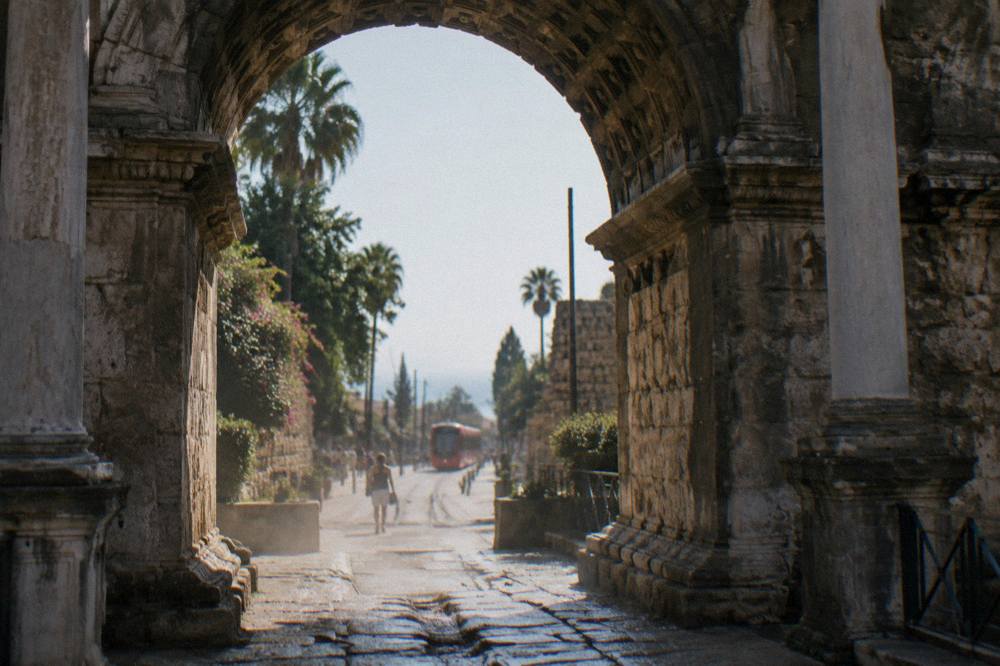 Stone gate of Hadrian's Gate seen from the street with the modern city beyond it