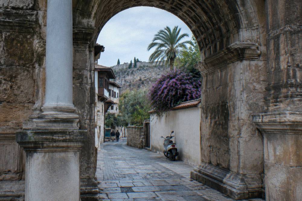 The stone doorway of Hadrian's Gate with a lane of Kaleici old town beyond