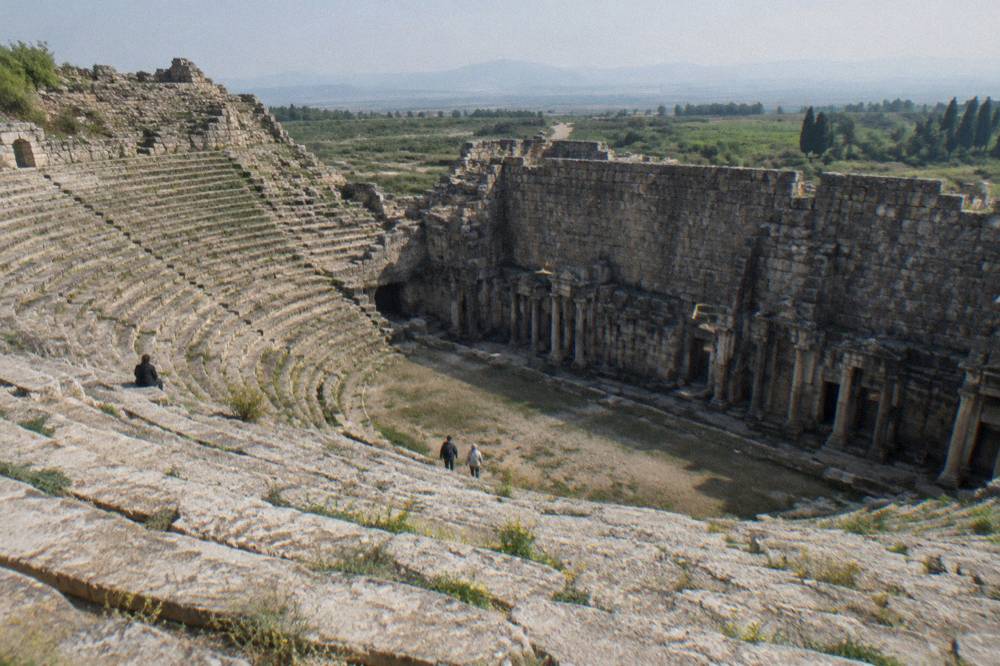 Rows of weathered stone seats in a closed ancient theatre under daylight