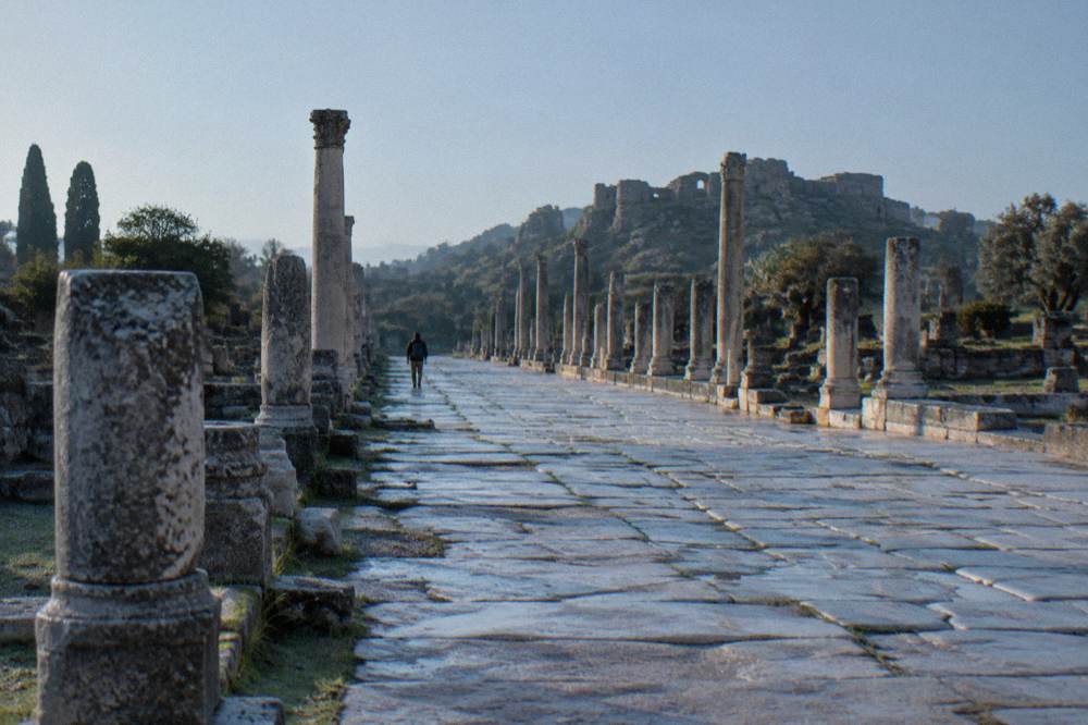 A long colonnaded stone street of an ancient city with visitors absent