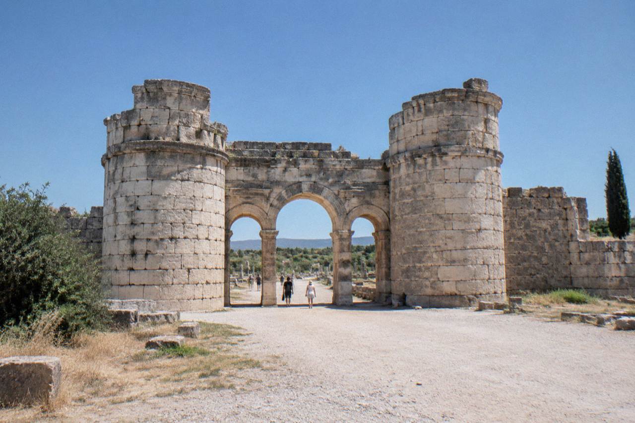 Stone ruins of an ancient Roman city gate under a clear sky in Antalya