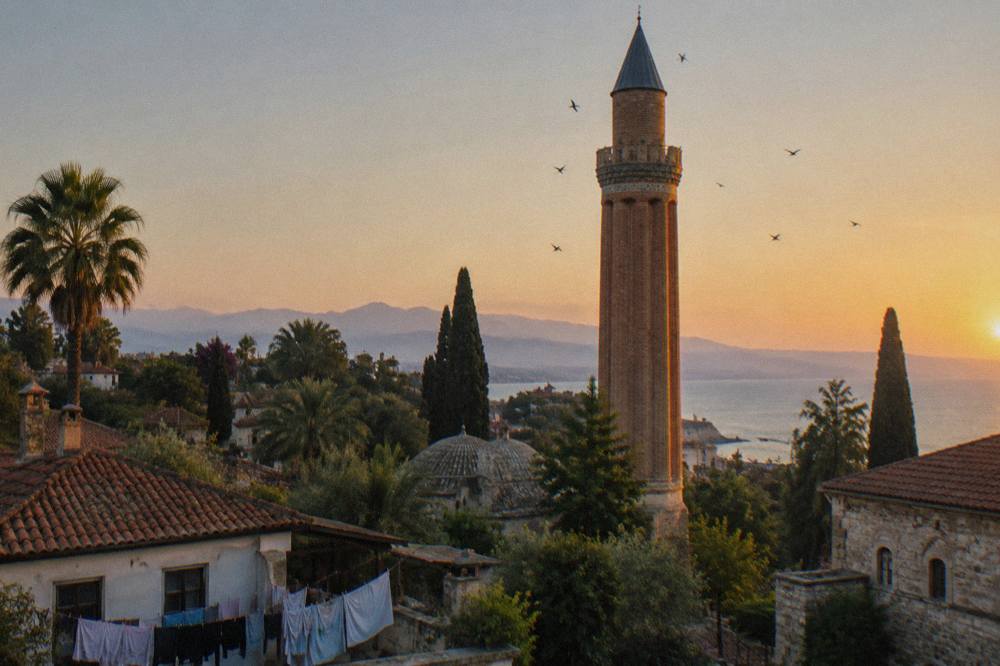 The fluted minaret of the Yivli Minaret complex rising above old town rooftops