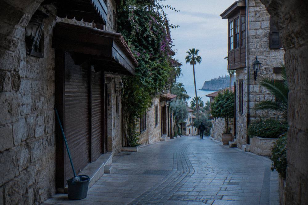 Narrow old town street with stone buildings and a stone archway in Antalya