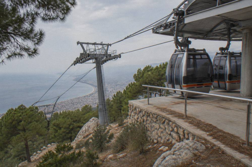 Cable car cabins parked at a hilltop station beside a calm sea