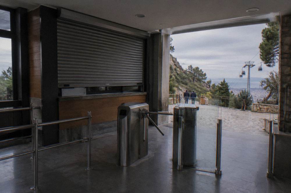 A ticket hall counter with closed shutters beside a coastal hillside path