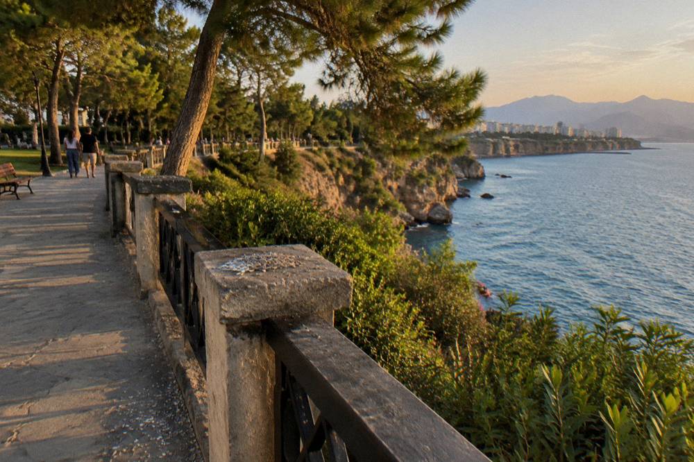 A clifftop park path above the sea with stone balustrades and green shrubs