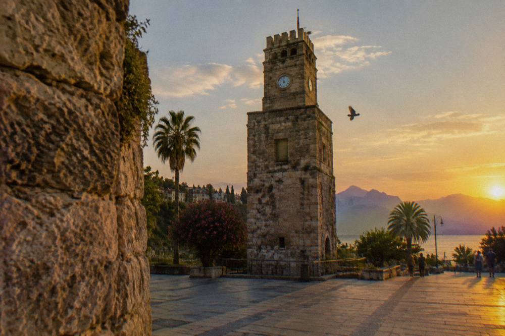Clock tower rising above an old stone gate in Antalya