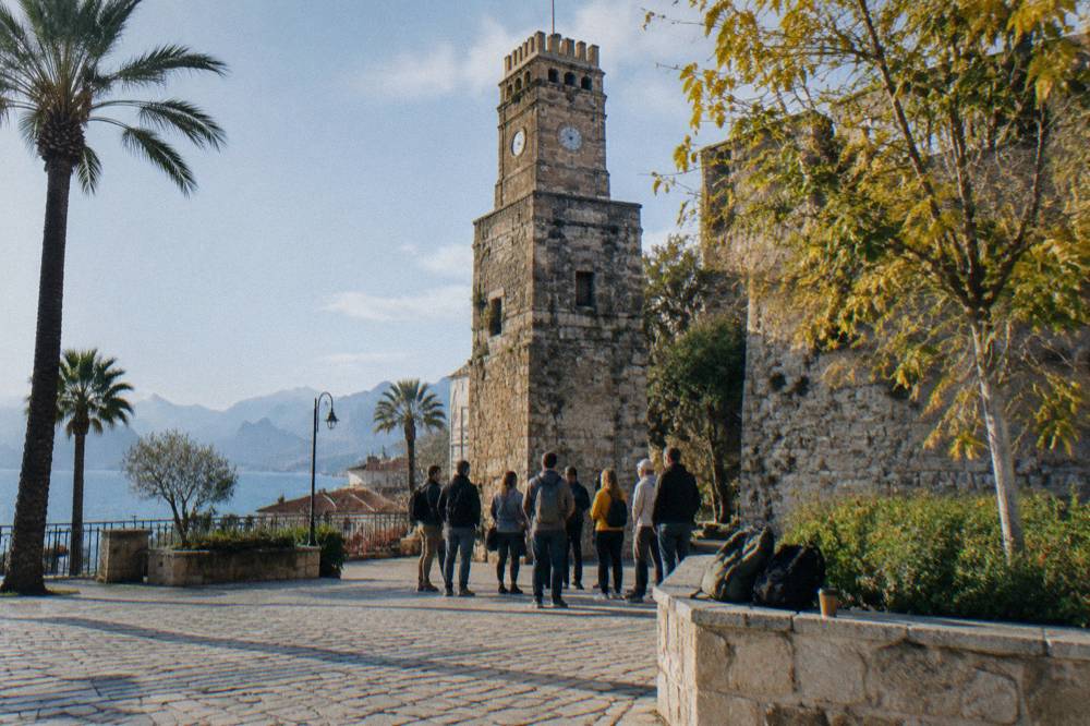 Walking tour group gathered at a stone tower meeting point in Antalya