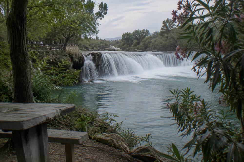 A waterfall cascading through green forest into a calm natural pool