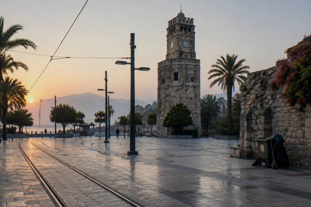 A stone clock tower beside a square at the edge of an old town quarter