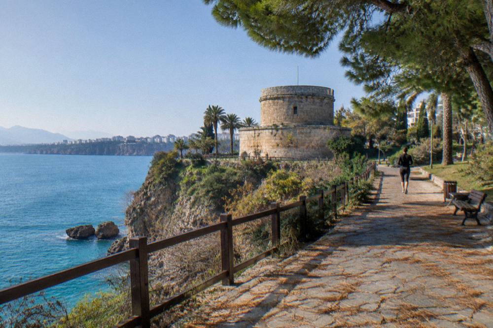 A clifftop park path running above the sea with a stone tower in the distance