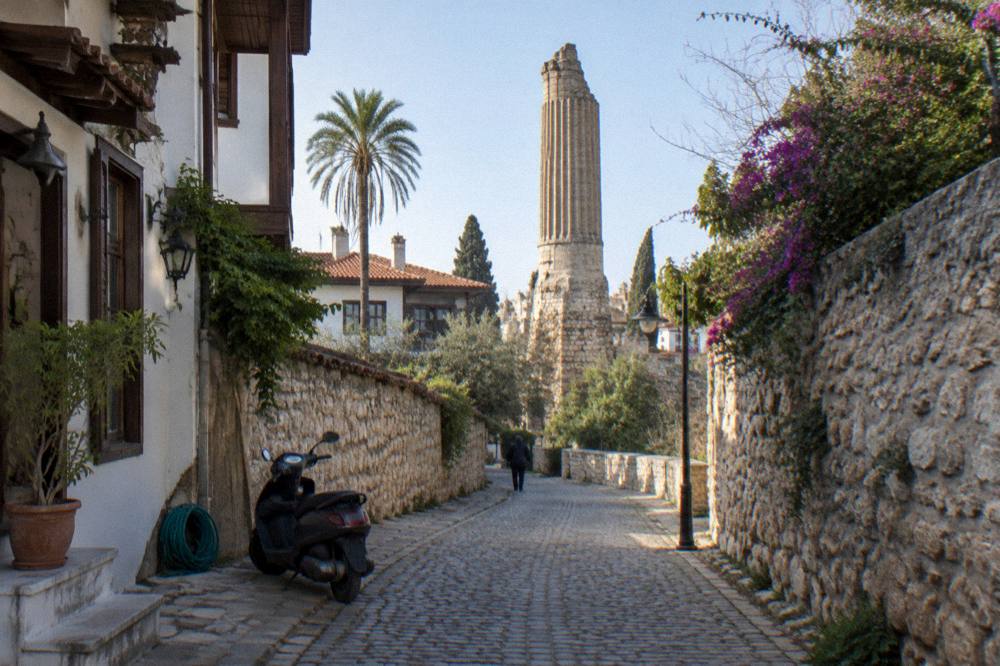 A narrow old town street with stone walls and a stone arch