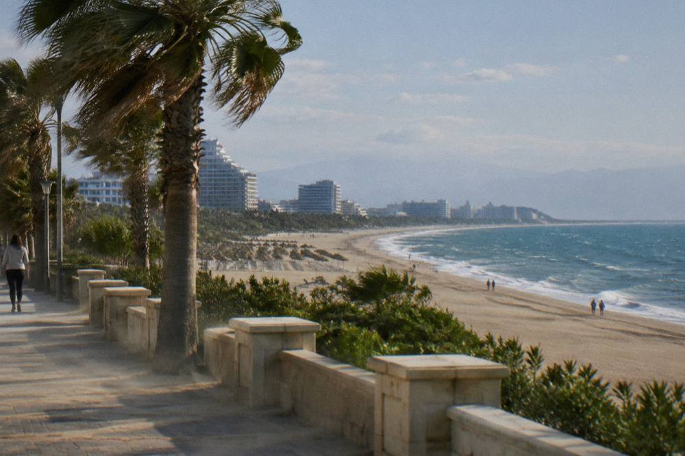 A long curved bay with a sandy beach along the water and a coastal promenade