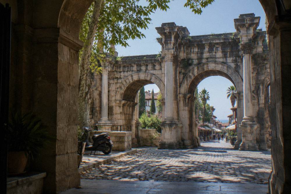 A Roman stone gate with three arches opening onto an old town street