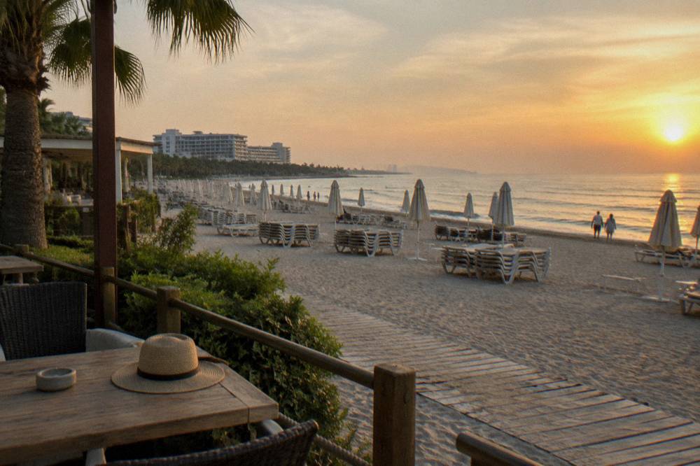Rows of sun loungers and parasols on hotel beachfront with open sand in the distance
