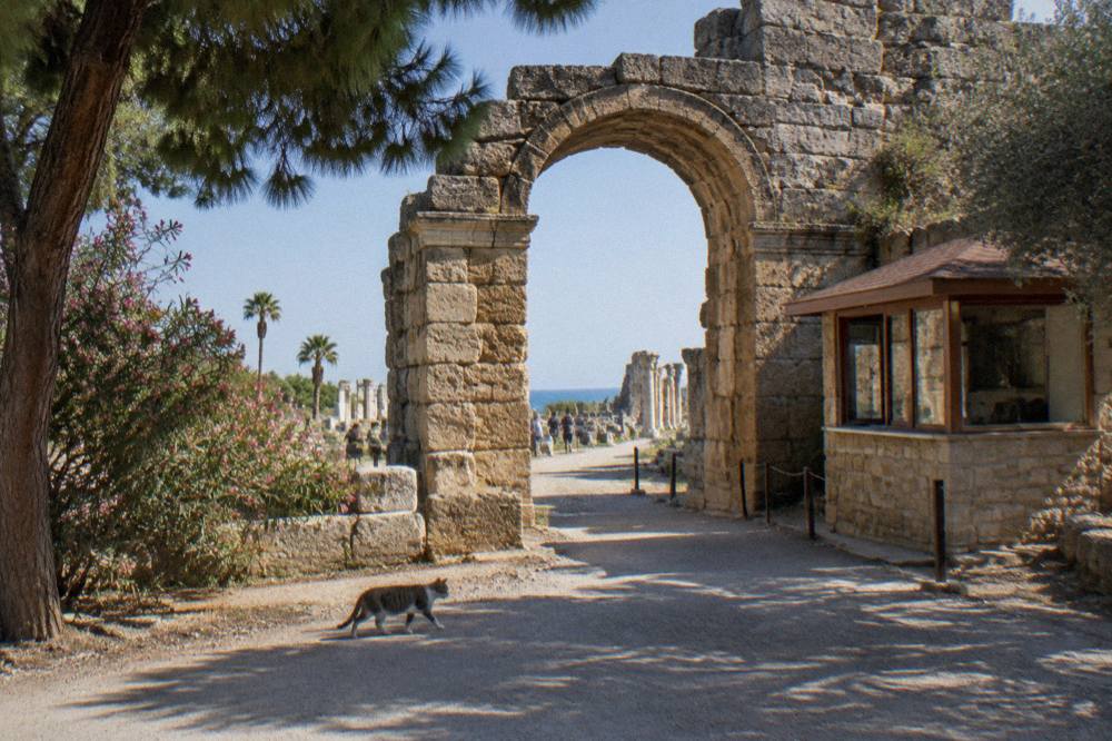 A stone archway of an ancient city site with a ticket gate beside it