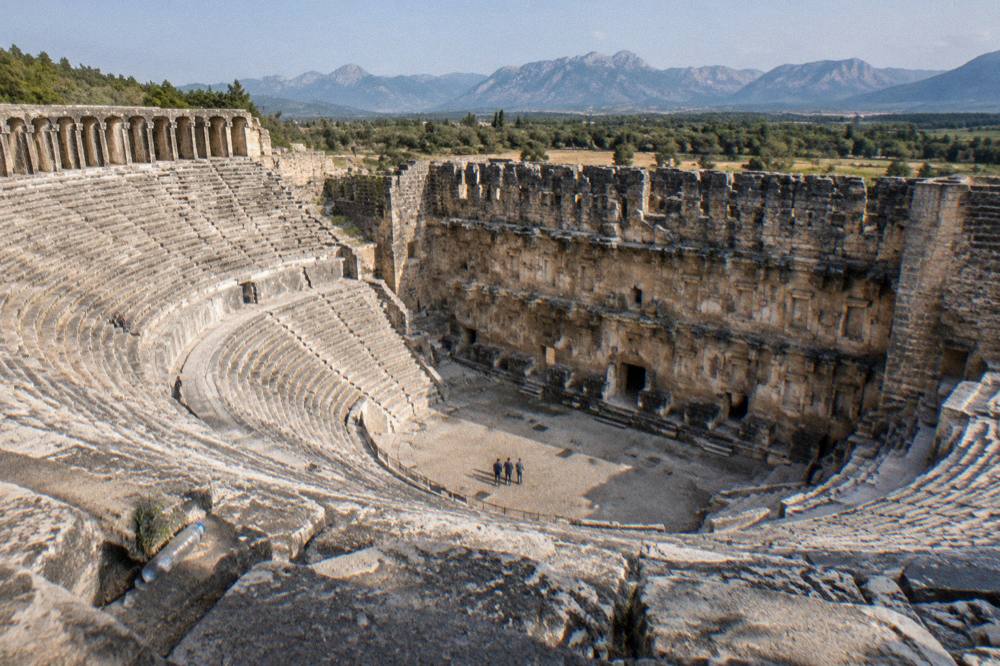A wide stone theatre seating area of an ancient site under a clear sky