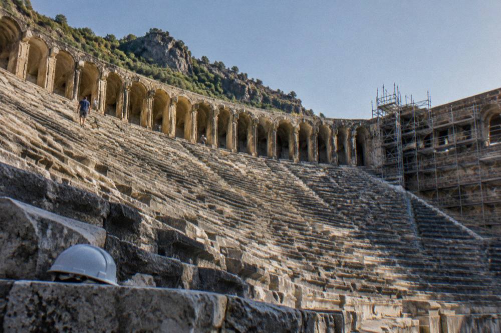 Rows of ancient stone seats at a Roman theatre under restoration scaffolding
