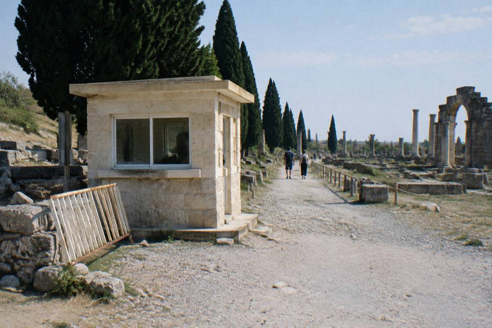 A stone ticket kiosk beside the entrance path of an ancient city site