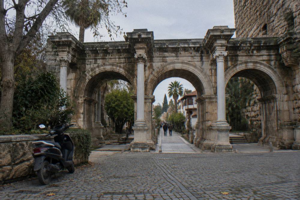 The ornate stone arches of a Roman city gate in an old town street