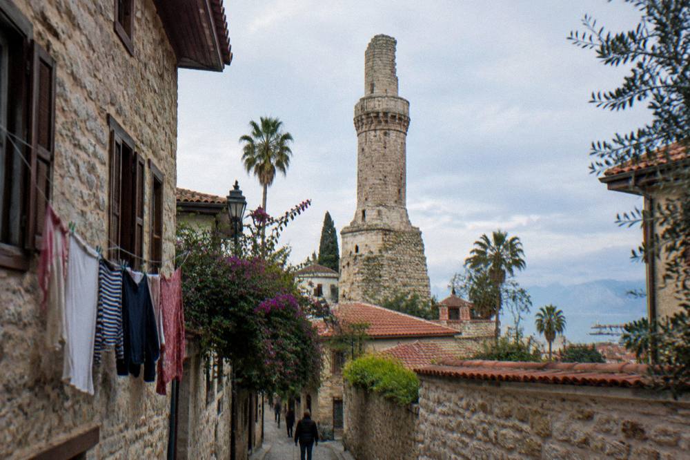 Narrow old town lanes with stone walls and a historic minaret rising above the rooftops
