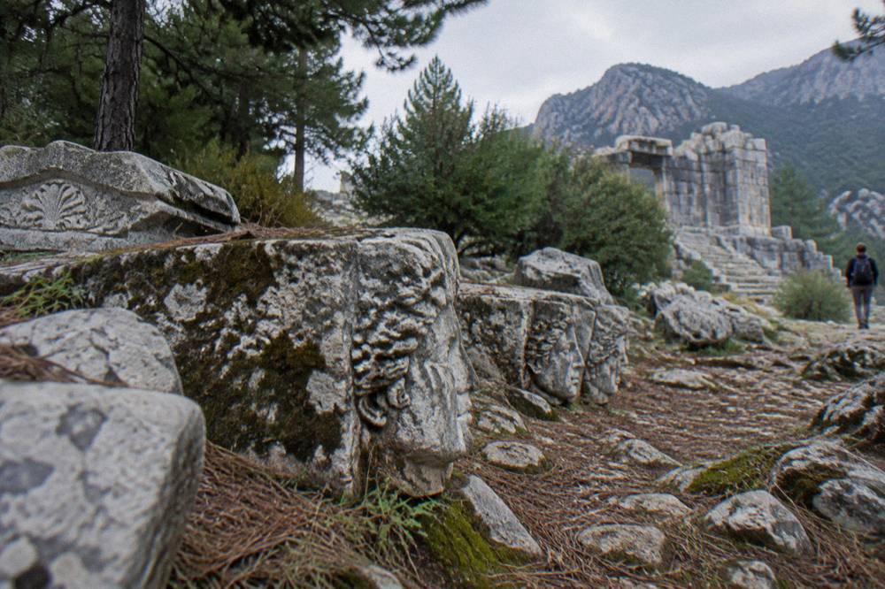 Weathered carved stone blocks on a forested mountainside ruin site